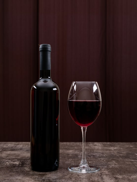 Foto grátis vista lateral vinho tinto em garrafa com copo na vertical