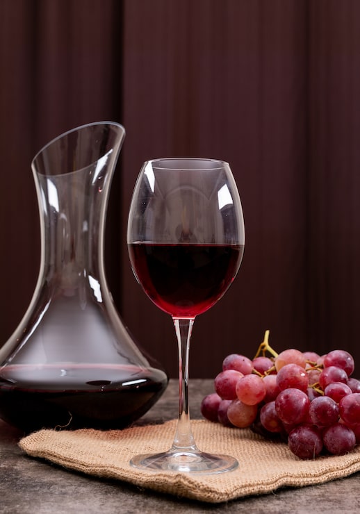 Foto grátis vista lateral vinho tinto em vidro com uva na vertical
