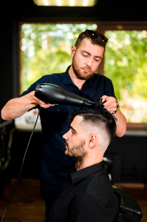 Kostenlose Foto friseur, der das haar seines kunden trocknet
