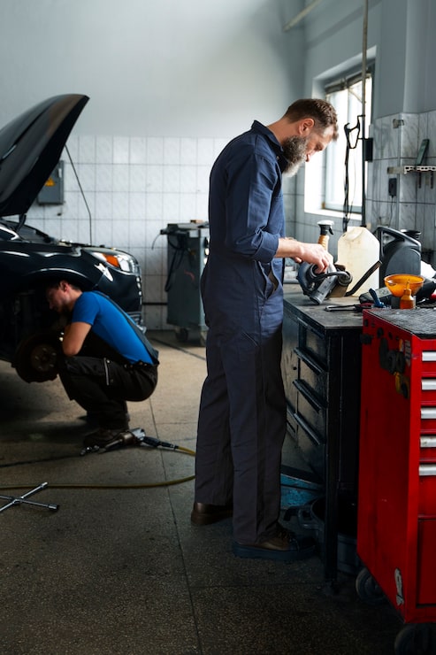 Kostenlose Foto männliche mechaniker arbeiten gemeinsam am auto im laden