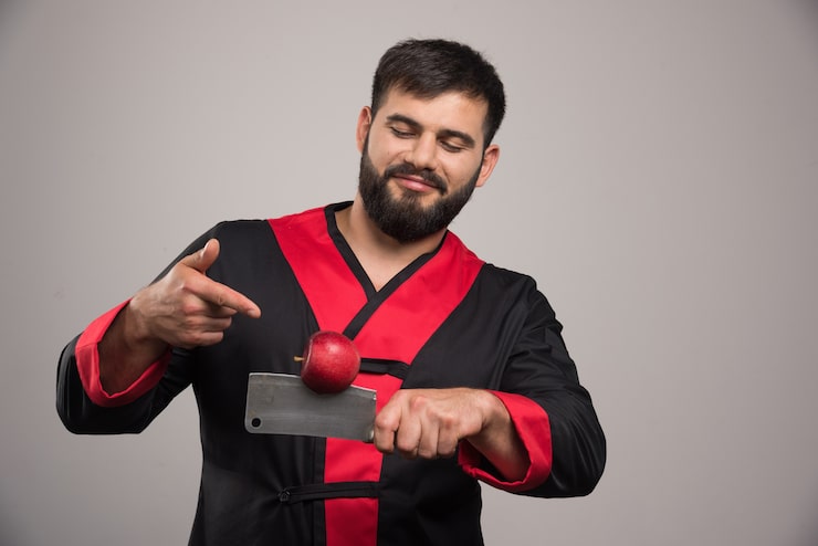 Kostenlose Foto mann mit bart, der auf roten apfel auf messer zeigt.