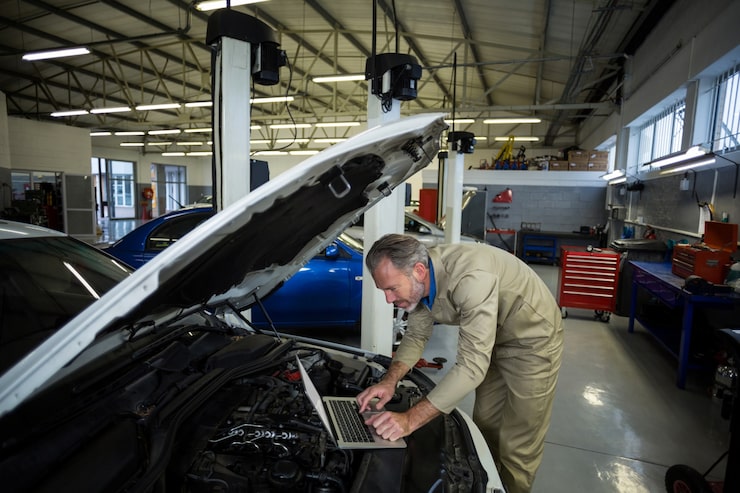 Kostenlose Foto mechaniker mit laptop, während ein auto motor gewartet