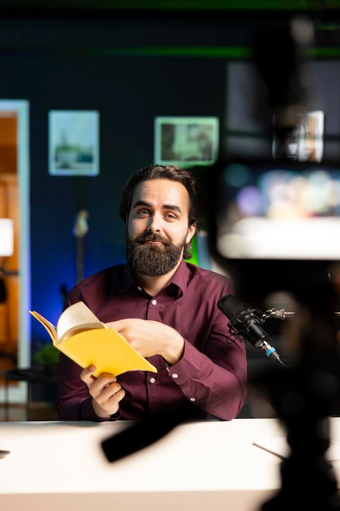 Kostenlose Foto medienstar liest die besten bücher des jahres und filmt mit professioneller kamera