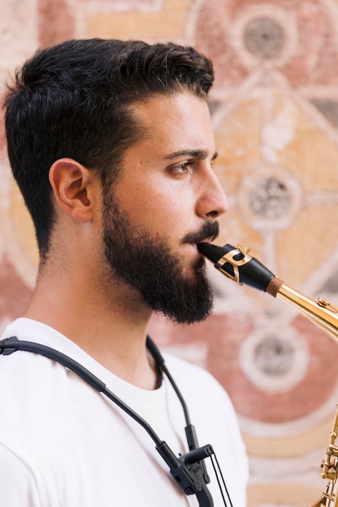 Kostenlose Foto seitwärts mannportrait, welches das saxophon spielt