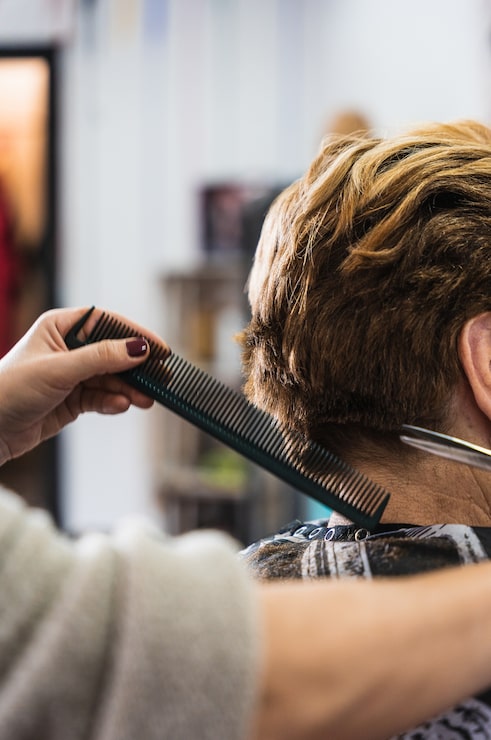 Kostenlose Foto vertikale nahaufnahme eines friseurs, der die kurzen haare einer frau in einem schönheitssalon schneidet