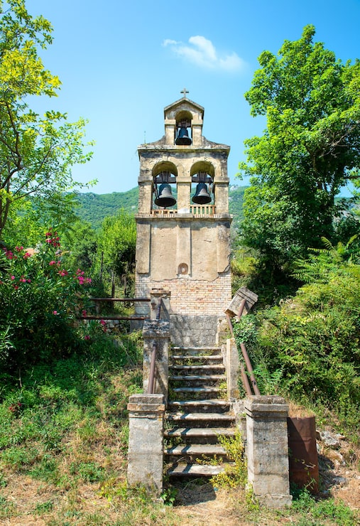 Foto campanario cerca del pueblo prcanj. montenegro. campanario separado en el fondo de la montaña.