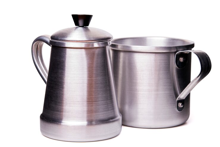 Foto ciérrese encima de vista de una taza y de un pote tradicionales de aluminio de té aislados en un fondo blanco.