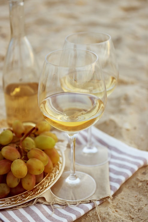Foto composição romântica de vinho branco e uva na areia da praia