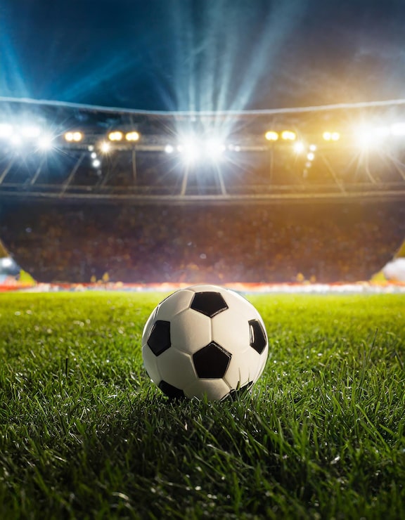 Foto después del juego, una pelota de fútbol en primer plano en el césped del campo de fútbol en un estadio lleno de gente con reflectores
