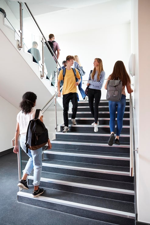 Foto estudiantes de secundaria caminando por las escaleras entre las lecciones en un ocupado edificio universitario