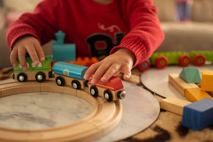 Foto fechado e macio focado na criança brincando de trem de brinquedo em cima da mesa