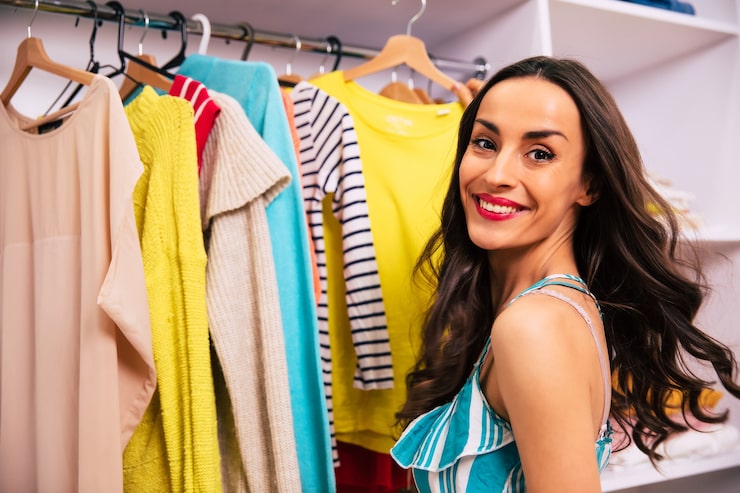 Foto una foto de vista lateral de una hermosa joven con un vestido de rayas, que está buscando un atuendo para usar con la ropa, colgada en su armario.