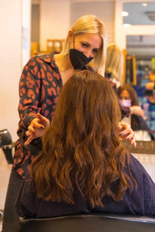 Foto friseur mit gesichtsschutzmaske, der dem kunden das ergebnis der frisur zeigt sicherheitsmaßnahmen auf dem vertikalen foto der covid19-pandemie