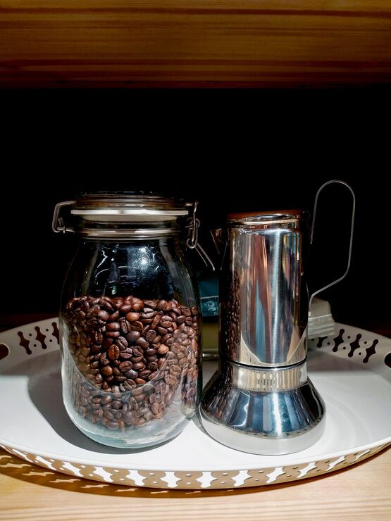Foto granos de café dentro de un frasco de vidrio con una bandeja de aluminio en la plataforma