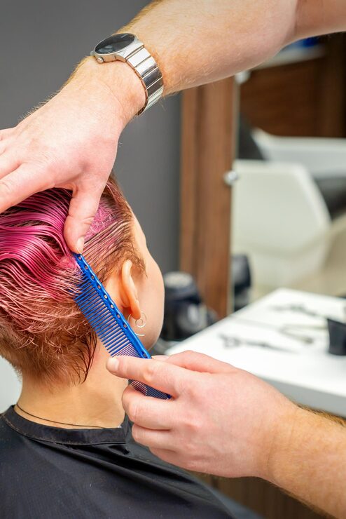 Foto hände des friseurs, der haare kämmt, die kurze rosa frisur für eine junge kaukasische frau in einem schönheitssalon machen.