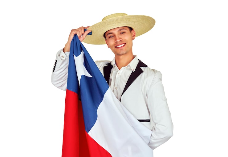Foto huaso chileno sonriente mostrando la bandera chilena mientras usa el tradicional sombrero de paja chupalla.
