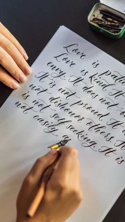 Foto kalligraphenhände schreiben satz auf weißbuch-bibelsatz über die liebe, die zierpflanzen einschreibt