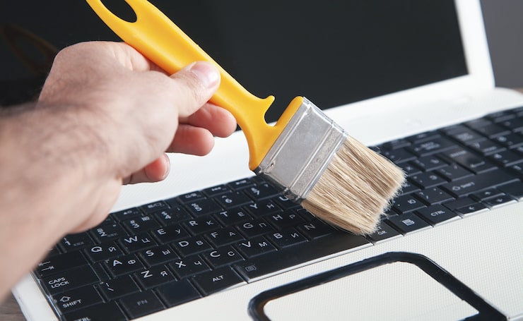 Foto limpieza del teclado del polvo y la suciedad con un cepillo.