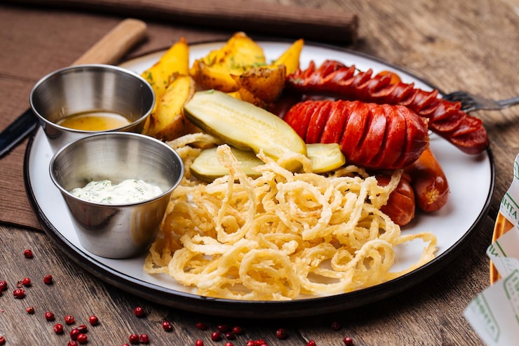 Foto mistura de salsichas com batata, cebola frita e molhos