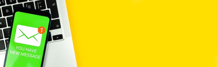 Foto novo ícone de mensagem na tela do celular comunicação empresarial conceito de internet e tecnologia teclado de laptop vista superior do banner de fundo foto