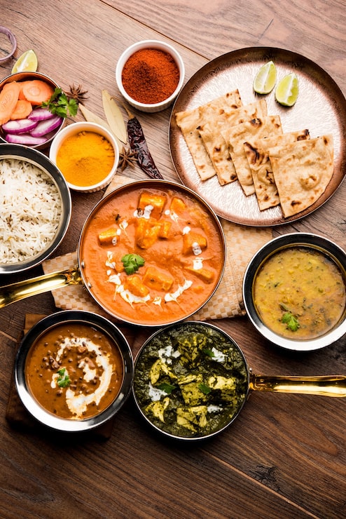 Foto o prato principal do almoço ou jantar indiano em grupo inclui paneer butter masala, dal makhani, palak paneer, roti, arroz etc, foco seletivo