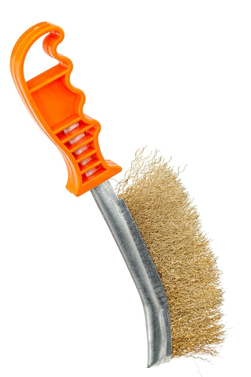 Foto pincel de alambre de bronce con mango de plástico naranja para la limpieza y pulido de equipos duros o metálicos aislados sobre fondo blanco