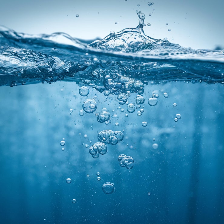Foto um salpico de água com bolhas que está sendo salpicado por um fundo azul