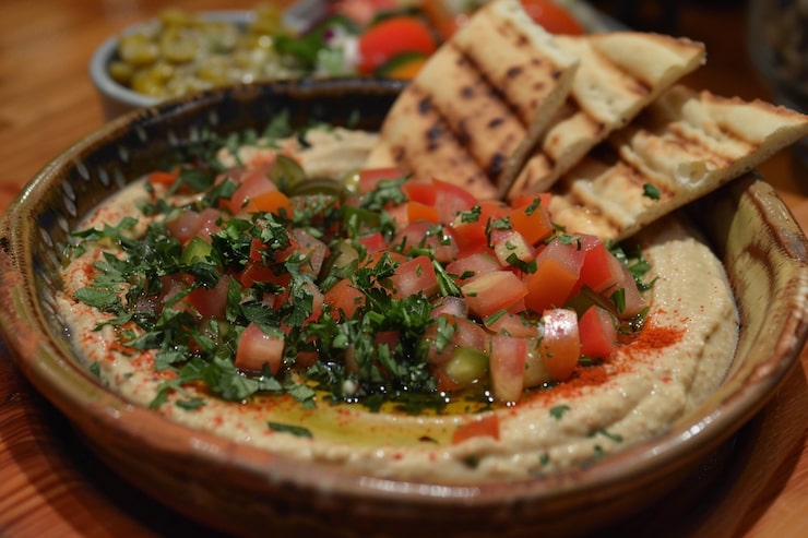Foto uma tigela de hummus cremoso com azeite de oliva e batatas fritas