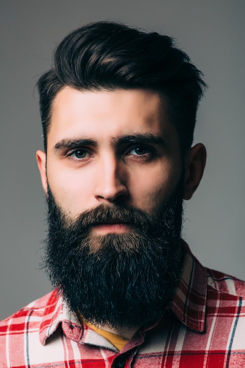 Gratis Foto portrett av kjekk skjeggete ung mann isolert på grå vegg