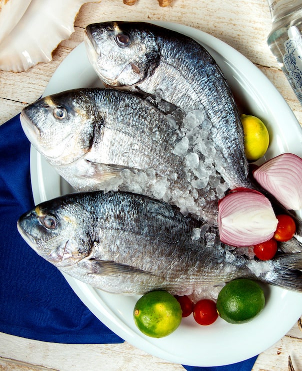Gratis Foto rå fisk plassert på tallerken med lime, løk, cherrytomat og is