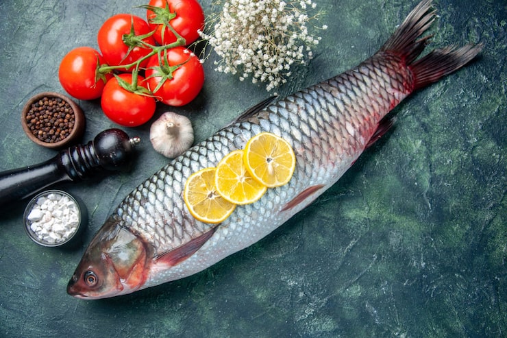Gratis Foto topputsikt fersk rå fisk med tomater og sitron på mørkeblå bakgrunn