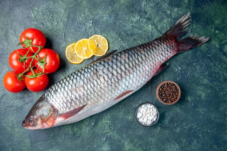 Gratis Foto topputsikt fersk rå fisk med tomater og sitronskiver på mørk blå bakgrunn