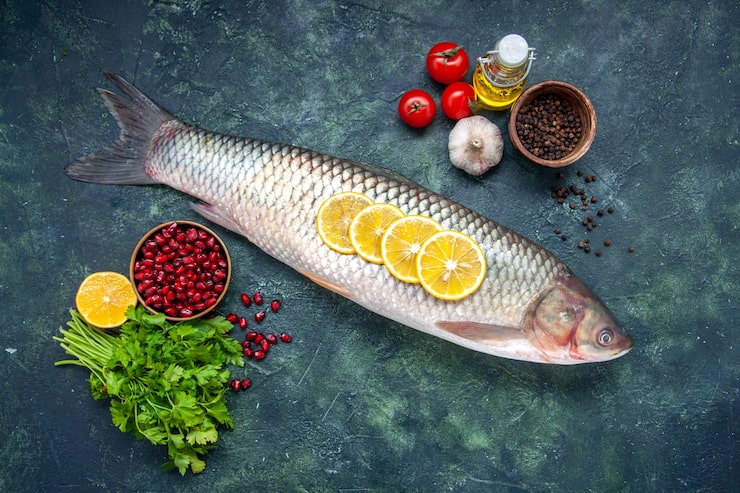 Gratis Foto topputsikt rå fisk tomater sitronskiver oljeflaske grønt på bord ledig plass