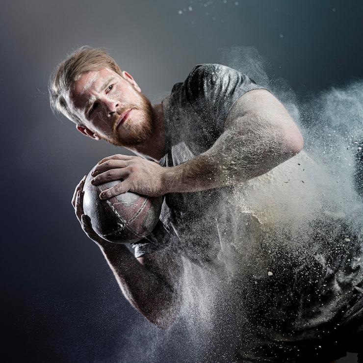 Gratis Bild atletisk manlig rugbyspelare som håller bollen med damm