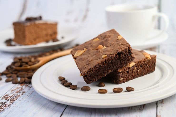Gratis Bild chokladbrownies på en vit tallrik och kaffebönor på en träsked.