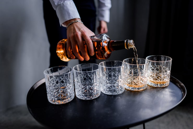 Gratis Bild en man häller en stark alkoholhaltig dryck i glaset.
