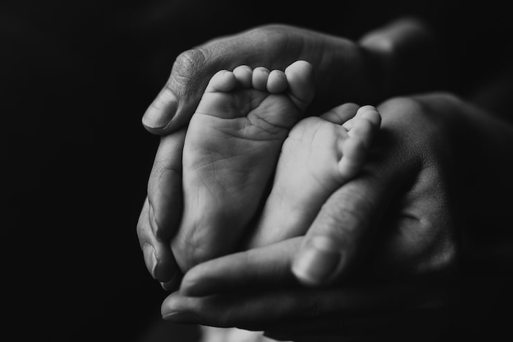 Gratis Foto gråtonebillede af babyfødder i en mors hænder