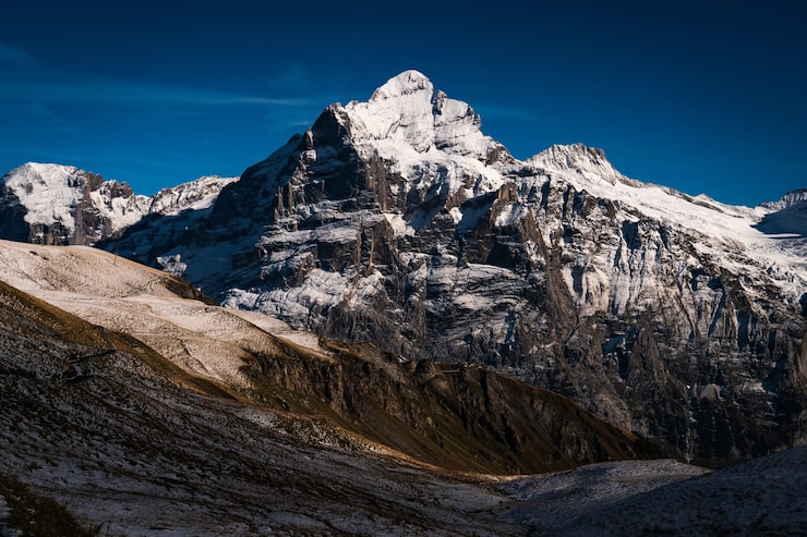 Gratis Bild höga klippiga berg täckta med snö under en klarblå himmel i schweiz