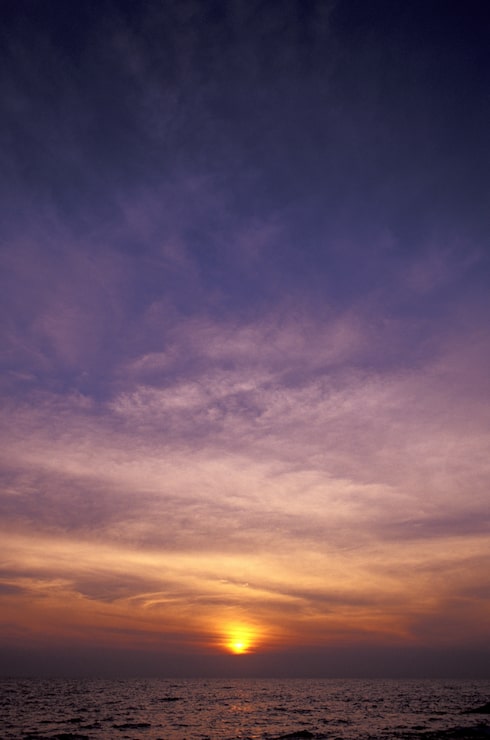 Gratis Foto lodret billede af en lilla og gul himmel over havet ved solnedgang
