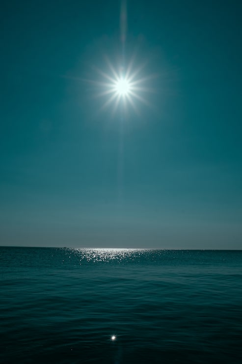 Gratis Foto lodret billede af et hav, der reflekterer solen med klar blå himmel