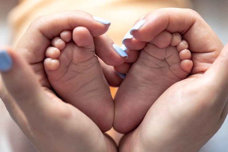 Gratis Foto mor holder benene på en nyfødt baby i sine hænder