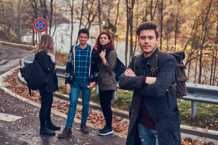 Gratis Foto rejser, blafferi, eventyr koncept. gruppe af unge vandrere, der står i vejkanten ved smuk efterårsskov.