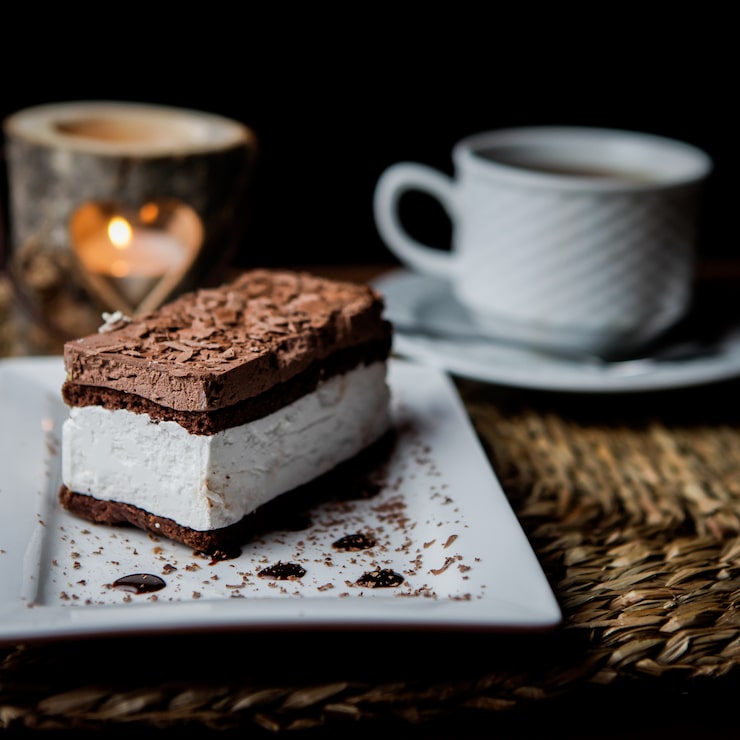 Gratis Bild sidovy av chokladtiramisu med kopp te och ljus och vit tallrik på servetter