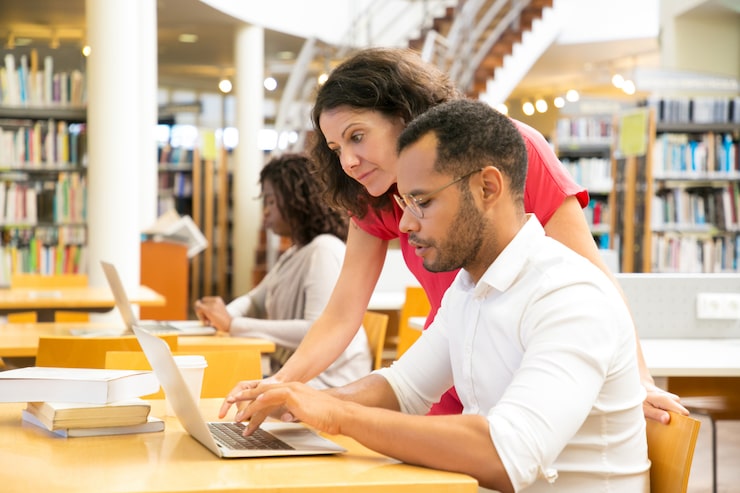 Gratis Bild sidovy av kollegor som arbetar med bärbar dator på biblioteket