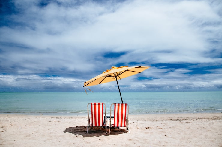 Gratis Bild strandparasoll och röda badstolar på en strand