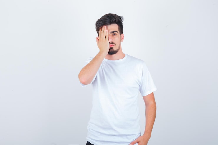 Gratis Bild ung man i t-shirt som täcker ögat med handen och ser säker ut