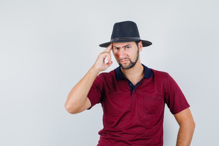 Gratis Bild ung man rör vid huvudet i t-shirt, hatt och ser arg ut, framifrån.