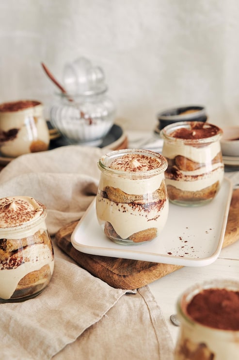 Gratis Bild vertikal bild av läcker tiramisu i små glas med puder på ett vitt bord