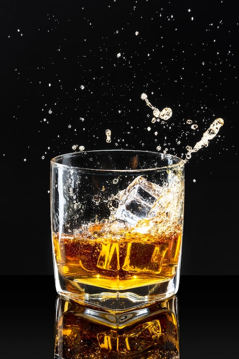 Gratis Bild whiskey med isbitar mot svart bakgrund