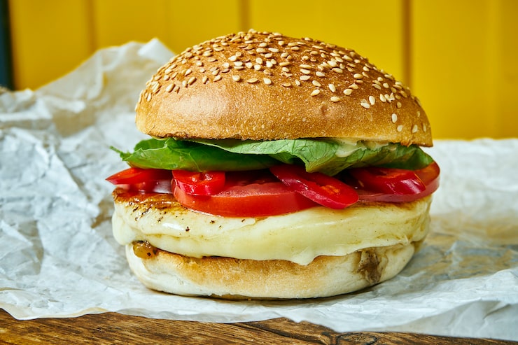 Photo bánh burger mọng nước với phô mai tan chảy và chả thịt trên giấy kraft. bàn màu vàng. đồ ăn đường phố, đồ ăn nhanh. cận cảnh..